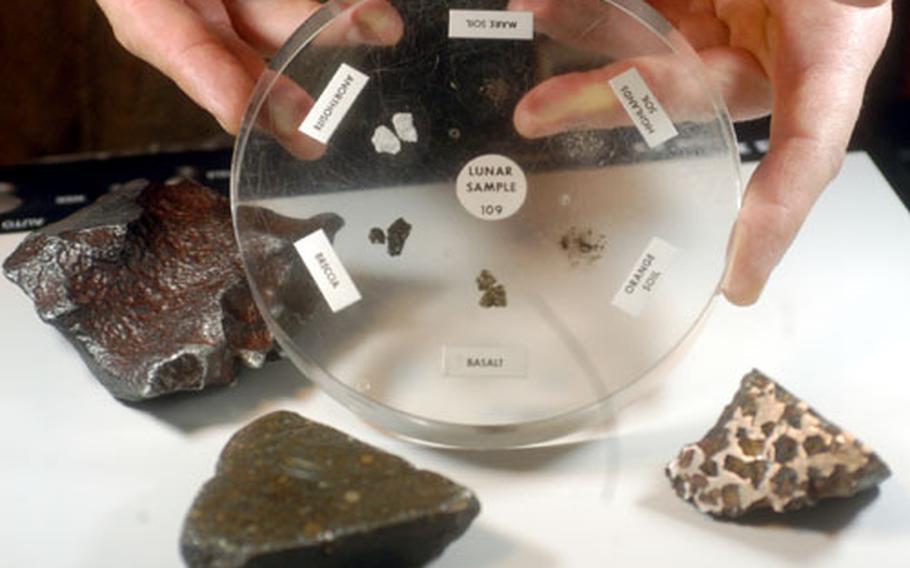 Greg Klaes, science teacher at Lakenheath Middle School, RAF Feltwell, England, holds samples of moon rocks encased in plastic. Surrounding them are meteorites that have struck the earth. Klaes is using the loaned samples in his classroom this week.