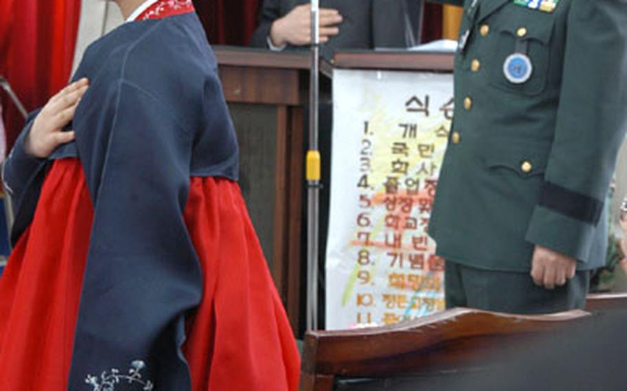 Jeon Hee-ryung, 13, and Republic of Korea Maj. Gen. Cho Young Rae, salute their country’s flag during Jeon’s sixth-grade graduation Wednesday morning.