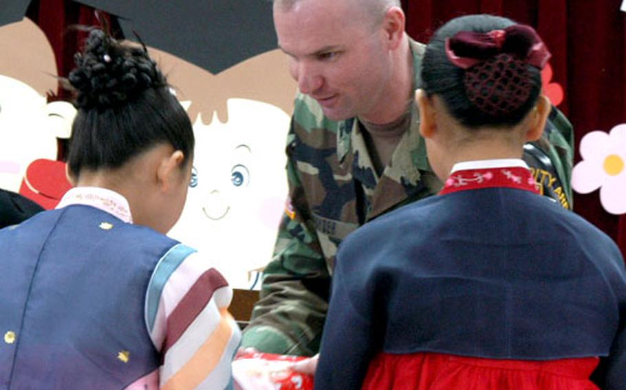 Lt. Col. Paul Snyder, the commander of the United Nations Command Security Battalion at the Joint Security Area in Panmunjom, presents gifts Wednesday to this year&#39;s two sixth-grade graduates of Tae Sung Dong Elementary School.