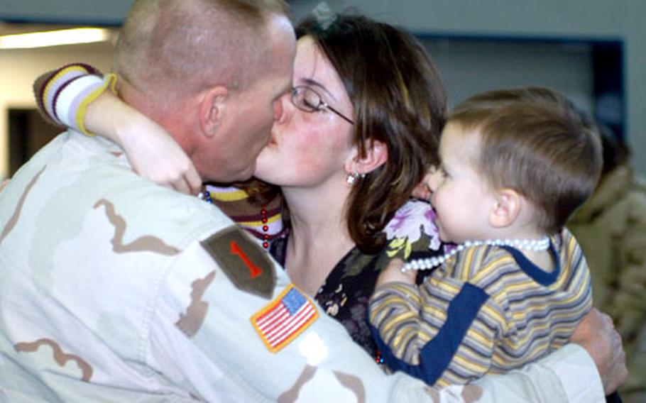 1st Sgt. Andrew Richard kisses his wife, Cathy, as 2-year-old Adam looks on Sunday in Vilseck, Germany.