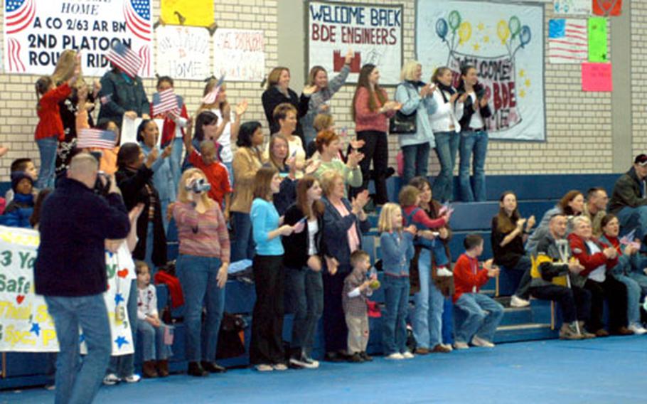 Family members cheer and wave flags as 2nd Battalion, 63rd Armor Regiment soldiers march into the Hilltop Sports Center Sunday in Vilseck, Germany.