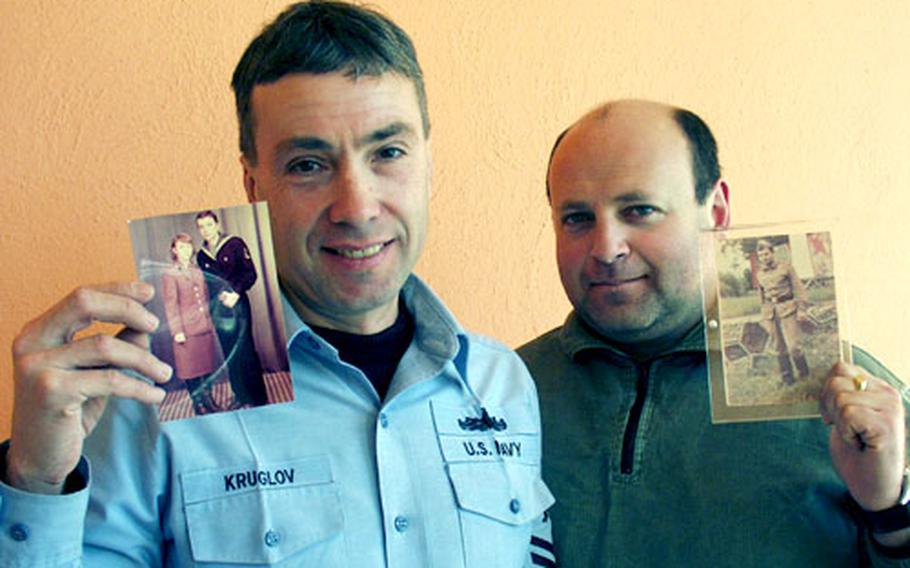 Petty Officers 1st Class Sergey Kruglov, left, and Vadim Gudin, both with the Naval Support Activity in Naples, Italy, hold up photos from when they served in the Soviet military in the 1980s.