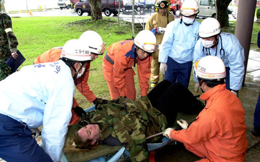 The Nirai Fire Department lifts Judith Canez on a stretcher during a mass casualty exercise at Torii Station, Okinawa, on Tuesday. Canez’s prosthetic abdominal wounds were treated by Army soldiers in an exercise designed to simulate a terrorist attack.