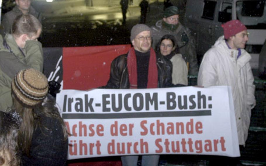 Protesters gather around a sign that reads “The Axis of Shame leads through Stuttgart” during a demonstration on Tuesday outside the U.S. European Command headquarters in Stuttgart, Germany.