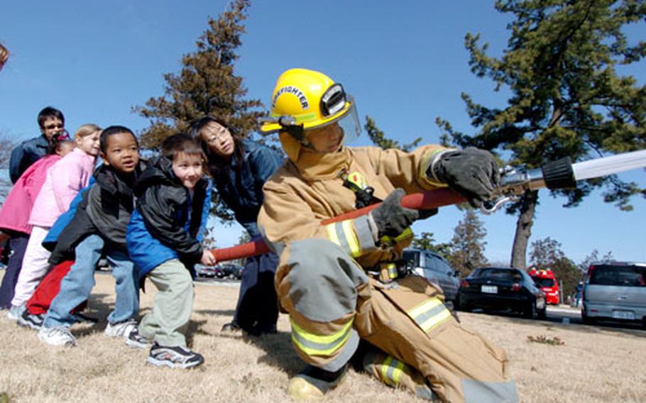 Children at the John O. Arnn Elementary School get an opportunity to handle a fire hose with the Sagamihara City Fire Department Wednesday.