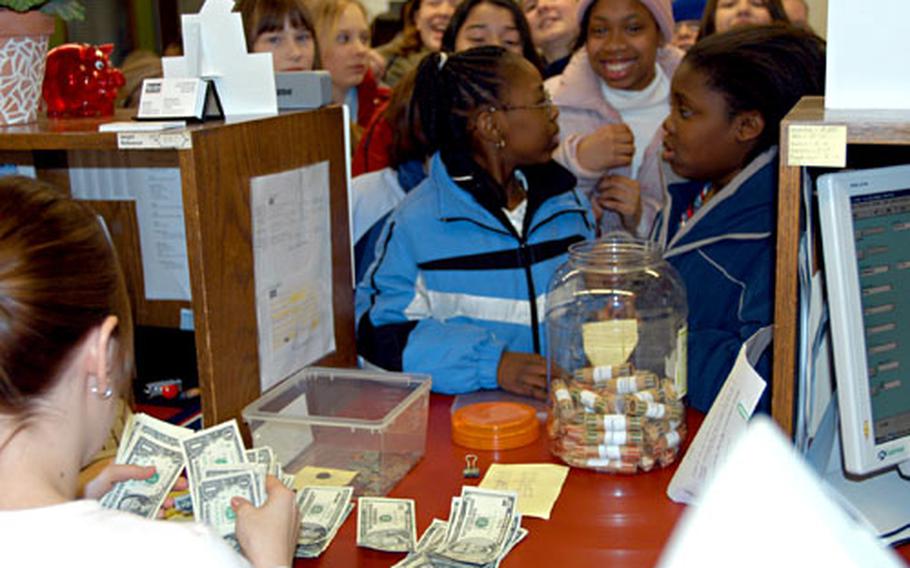 Service Credit Union teller Lisa Bonnes counts money raised by Bamberg Elementary School sixth-grade students as they all squeeze up to the window Thursday. The sixth-grade classes raised more than $300 of the approximately $1,300 collected by the school pupils for tsunami relief.