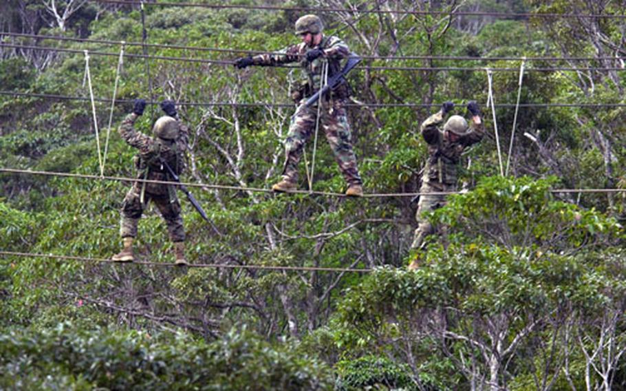 As one member crosses a ravine using a three-strand rope bridge, two teammates head the opposite direction.