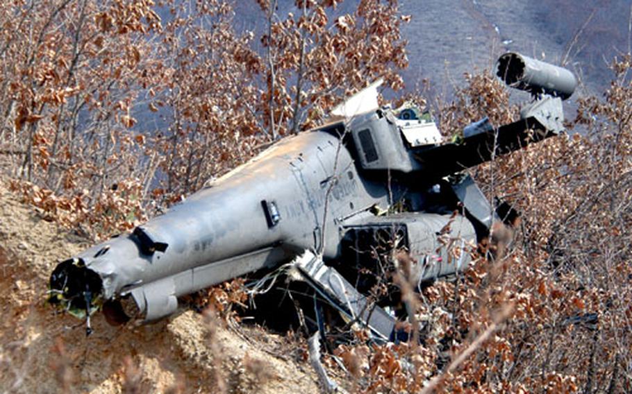 The wreck of a 1st Battalion, 2nd Aviation Regiment Apache attack helicopter perches precariously on a South Korean hillside after going down Saturday at Twin Bridges Training Area.