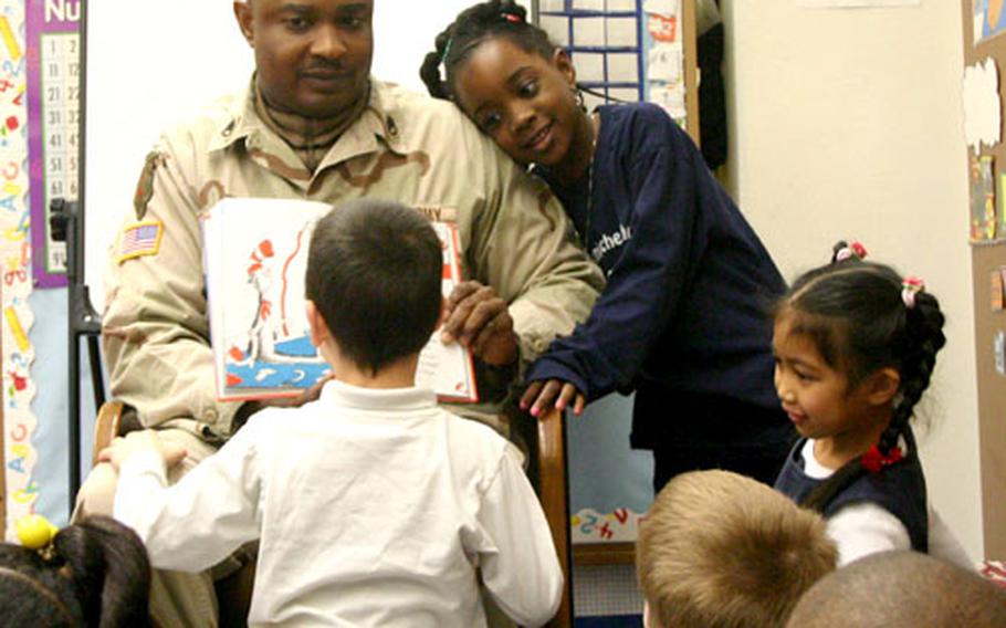Makayla Young, a first-grader at Schweinfurt Elementary School, leans on the shoulder of her dad, Staff Sgt. Cedric Young of the 1st Battalion, 18th Infantry Regiment as he shows Bryan Rubenacker a picture from Dr. Seuss&#39;s "Cat in the Hat" book. Parents were encouraged to go to school to read to students on Read Across America Day.