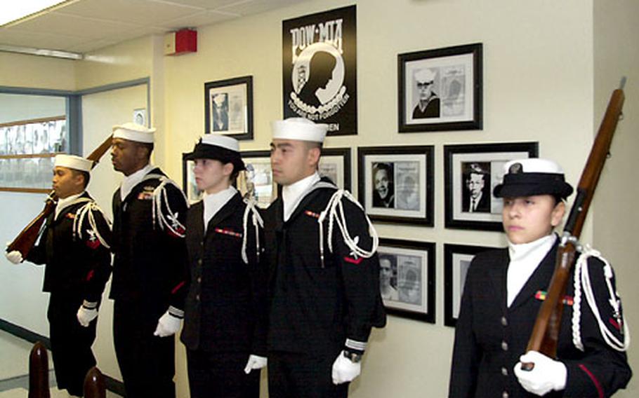 Veterans and a Navy honor guard pay tribute to the hospital corpsmen whose photos were retired from the POW/MIA wall at the Camp Lester, Okinawa, U.S. Naval Hospital on Wednesday.
