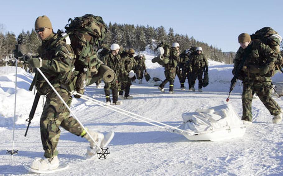 A U.S. Marine wearing snowshoes and using ski poles makes his way through the Norwegian snow.