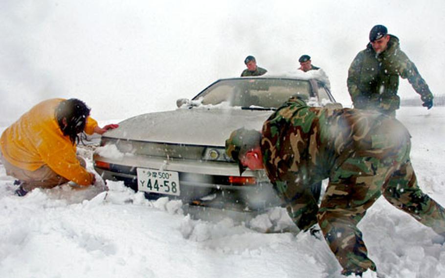 Members of the 374th Security Forces Squadron, Yokota Air Base, Japan, assist Master Sgt Terry Cross, right, from the 374th Mission Support Squadron, and his daughter Shannon Cross, left, after her car got stuck during a snow storm.