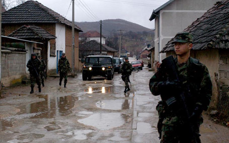 Spc. Randolf Labastida, from the 1st Battalion, 160th Infantry, patrols the muddy streets of the Serbian village of Pasjan on Saturday, near the U.S. military facility at Camp Monteith, Kosovo. Troops regularly patrol local villages to provide a reminder of the presence international peacekeepers retain in the region.
