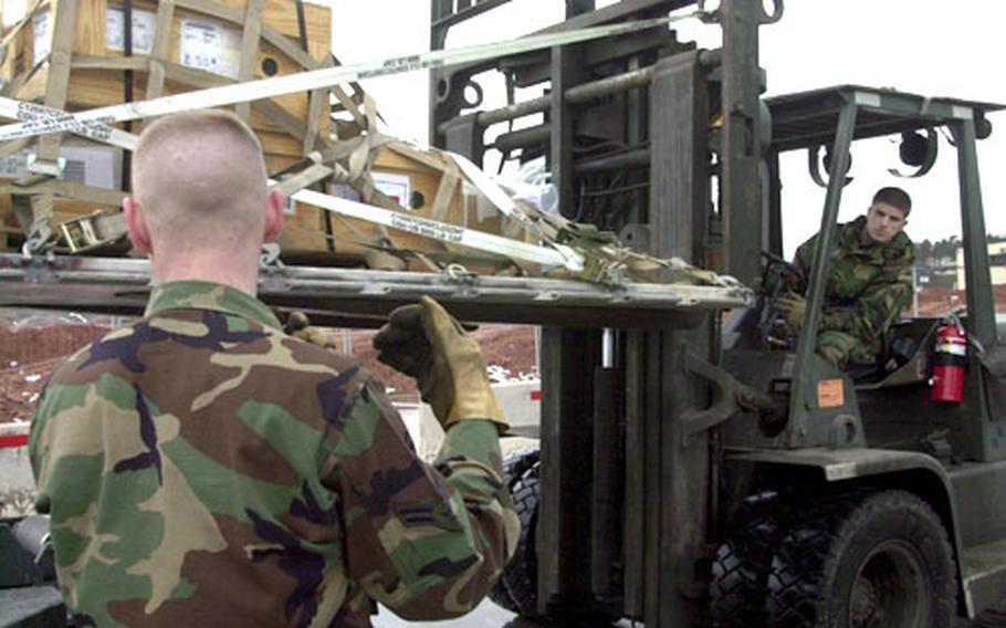 Airman Zach Fuchs, left, helps a fellow airmen place a pallet on a loader at Ramstein Air Base in Germany.