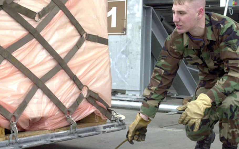 Airman Zach Fuchs helps load a pallet onto a forklift.