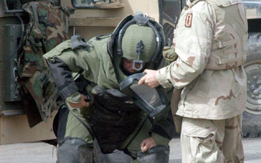 Army Staff Sgt. Vernon Smith, left, of Tallahassee, Fla., an explosive ordnance disposal team member from the 766th Ordnance Company, is helped into a protective suit by Pfc. Wade Harrington, of Steinhatcher, Fla., after a roadside bomb was found in northern Baghdad on Monday.
