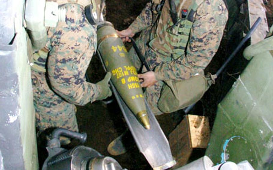 Marines, who endured a cold, muddy week at Camp Fuji, load a Howitzer.