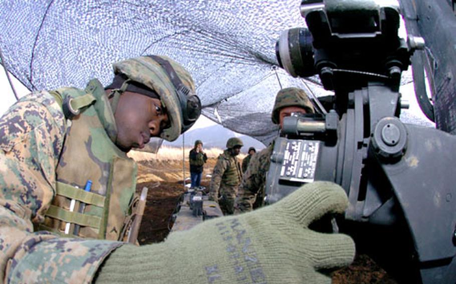 Pfc. Jody Grier adjusts the elevation and correction controls on a M119A howitzer.