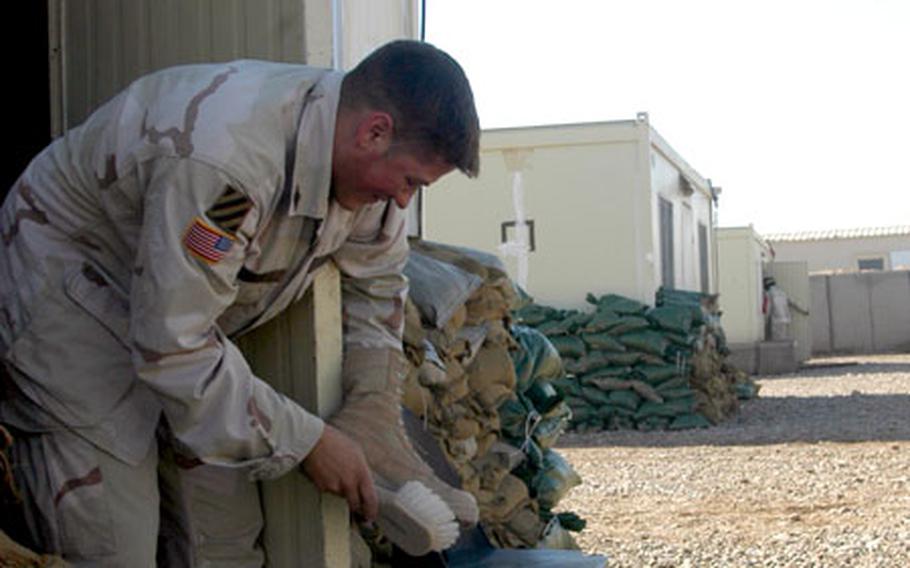 Sgt. Kevin Wigger of Fruitport, Mich., and Headquarters Company, 3rd Brigade Troop Battalion, 3rd Brigade Combat Team, brushes the dried mud off his standard issue desert boots on Sunday at Forward Operating Base Warhorse in Baqouba, Iraq.
