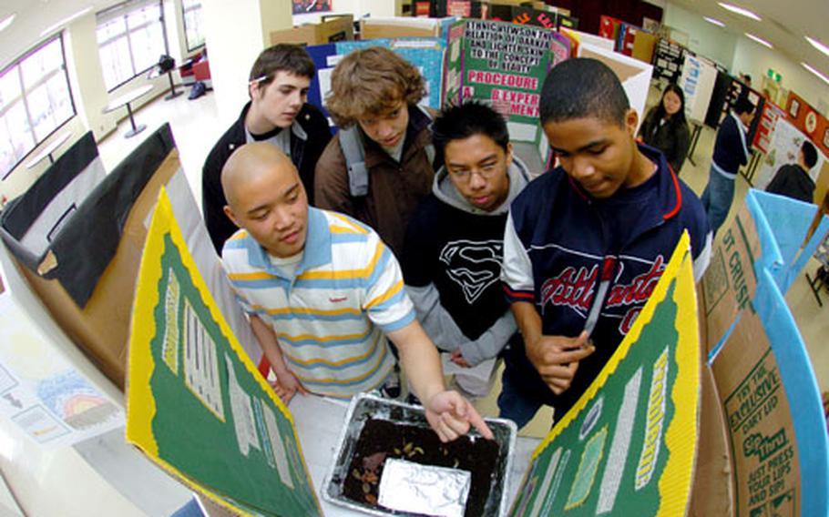 Jonathan Delos Santos, bottom left, explains his project on sow bugs to (top left to right) Michael Reilly, Dan Appleman, Richard Bendo and Robert Benton at the Kinnick High School Science Fair on Friday at Yokosuka Naval Base, Japan.