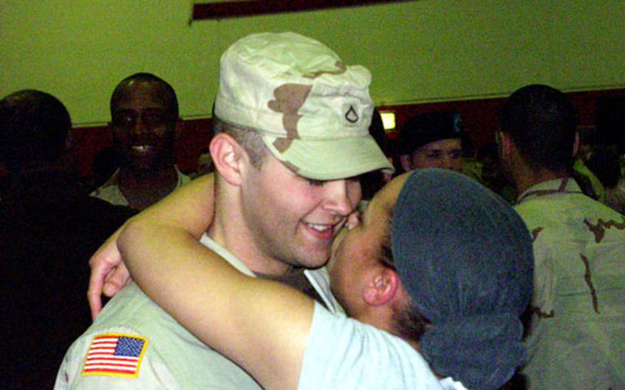 Pfc. Roy Phoenix, left, is embraced by his girlfriend Spc. Sandra Golden following a welcome home ceremony at the Sullivan Barracks Gymnasium.