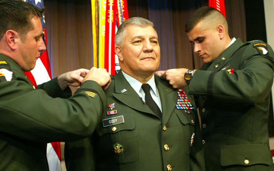 Gen. Richard A. Cody’s two sons, Capt. Clint Cody, left, and Capt. Tyler Cody, both with the 101st Airborne Division, pin four stars on his shoulders at the Pentagon auditorium July 2, 2004.