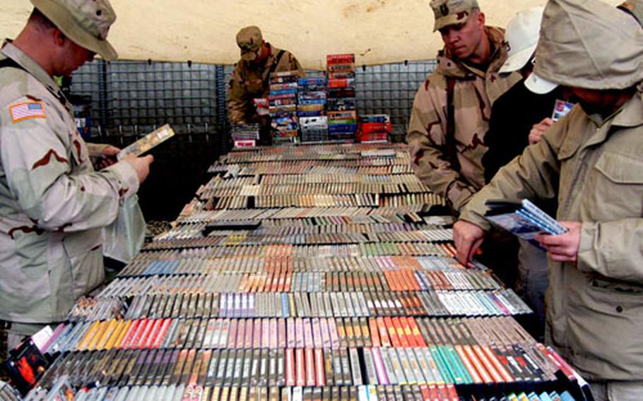 U.S. troops search through DVDs at a local bazaar at Bagram Air Base, Afghanistan. The bazaar is held on the base every Friday.
