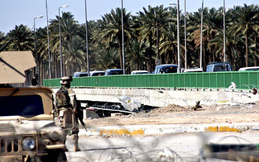 A soldier with Company A, 1st Battalion, 9th Field Artillery Regiment from the 2nd Brigade, 3rd Infantry Division watches vehicles line up across the Jisr Diyala Bridge in southeast Baghdad at a traffic checkpoint Wednesday.