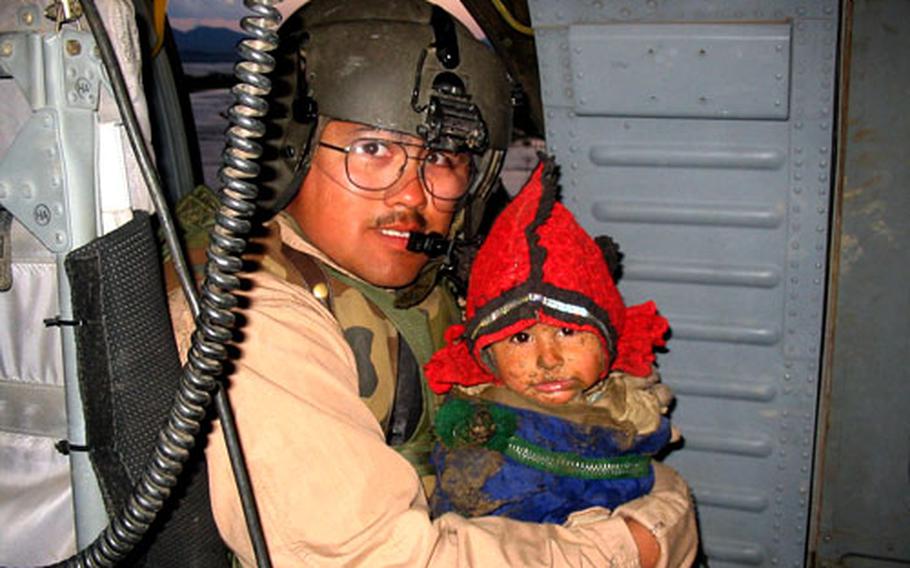 Sgt. Ryan Garfield, UH-60 Black Hawk crew chief, holds a child rescued from rising floodwaters near the southern Afghanistan area of Deh Rawod. Garfield is a member of Company A, 2nd Battalion, 25th Aviation Regiment, from Kandahar Airfield, Afghanistan.