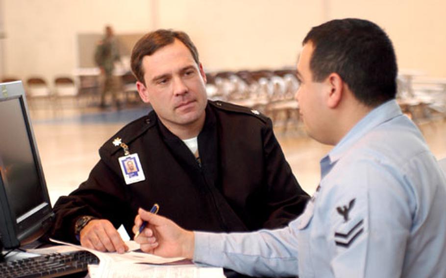 Navy Cmdr. Mark Businger, left, helps Yeoman 2nd Class Elias Loy with some paperwork as part of a predeployment session held by the 80th Area Support Group in Chievres, Belgium. While their numbers aren&#39;t large, more U.S. troops in the Benelux are deploying to Iraq and Afghanistan.