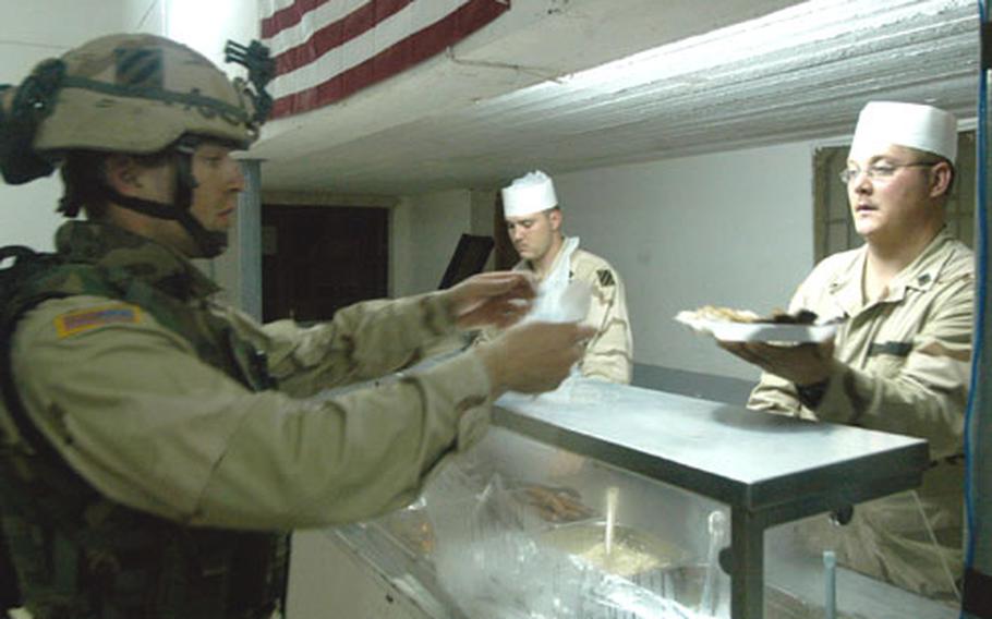 Spc. Anthony Turner, left, of 2nd Battalion, 69th Armor Regiment, gets a plate of food from Spc. William Blasingame of Guymon, Okla., and 1st Battalion, 10th Field Artillery Regiment, at one of the dining facilities at Forward Operating Base Gabe in Baqouba, Iraq. In the background is Spc. Dustin Chaney of Cocoa Beach, Fla. Chow halls and their all-you-can eat offerings help some soldiers pack on the pounds.