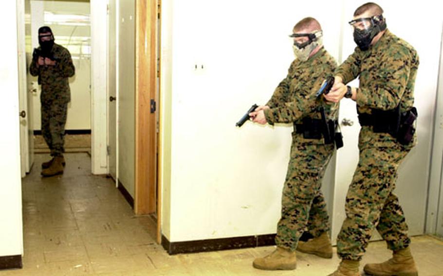 An armed "suspect" waits to ambush two Marine military policeman during training in the old Sada Housing on Camp Foster Tuesday.