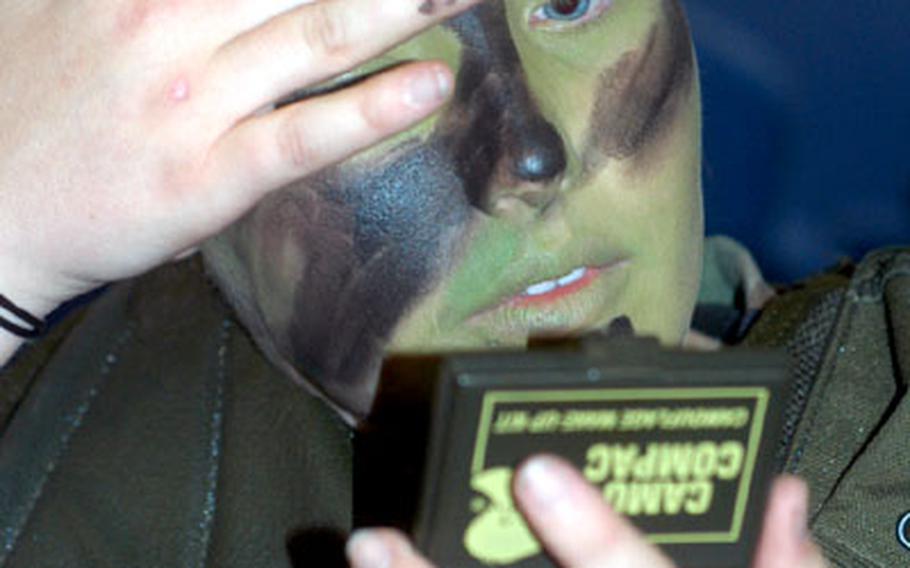 Airman Jennifer Hunt of the 100th Security Forces Squadron at RAF Mildenhall, England, applies camouflage paint to her face during training near the base.