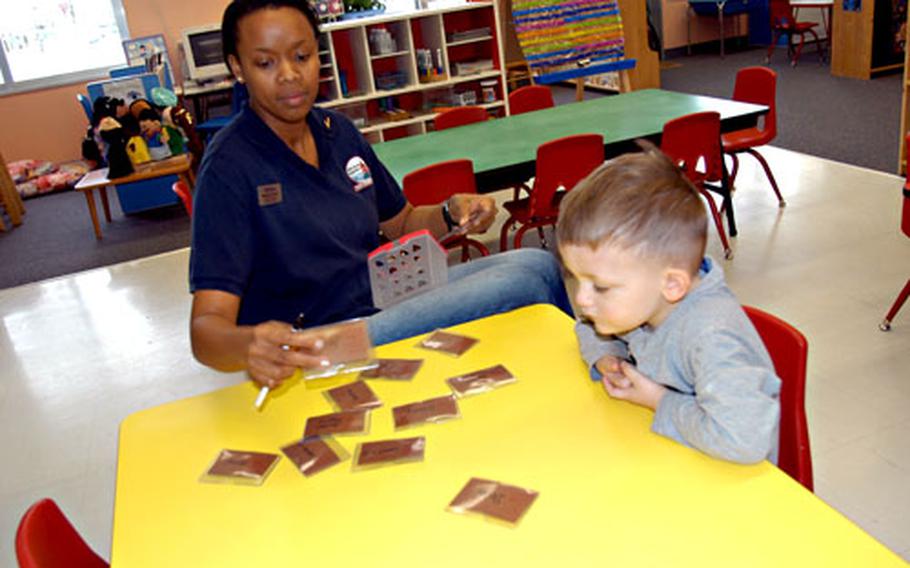 Child-care provider Nicole Cyrus and Beau Redmond, 3, look over tickets that each child in the Yoiko Child Development Center&#39;s preschool class uses to visit the various play and activity centers in the classroom.
