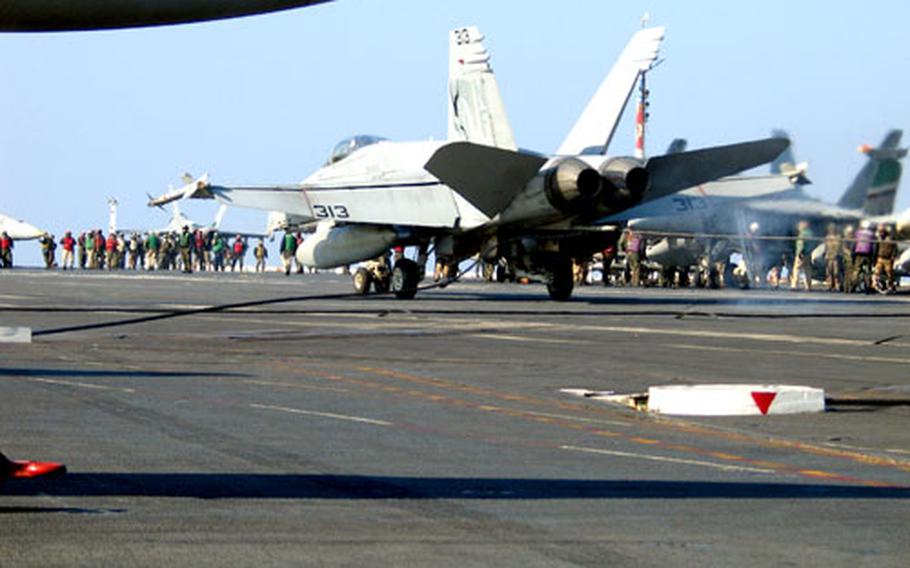An aircraft snags the arresting cable during a landing aboard the USS Kitty Hawk. The thick cable is pulled out until the jet stops, often close to the deck&#39;s other edge. The force adds tremendous tension to the wire.