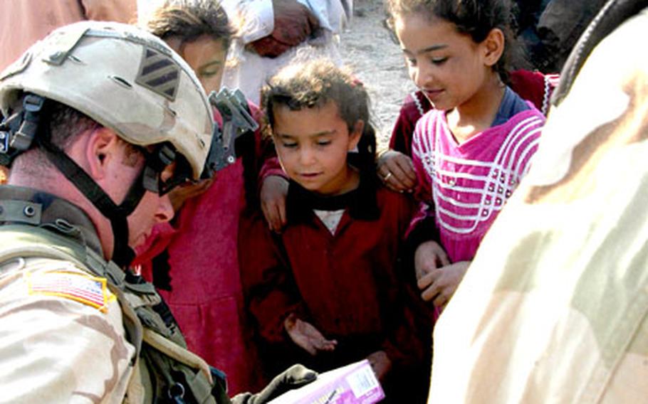 First Lt. Jimmy Ryan, a platoon leader with Company A, 1st Battalion, 15th Infantry Regiment, hands out bubble-makers to children Wednesday during a patrol in Ad-Daluiyah, Iraq.