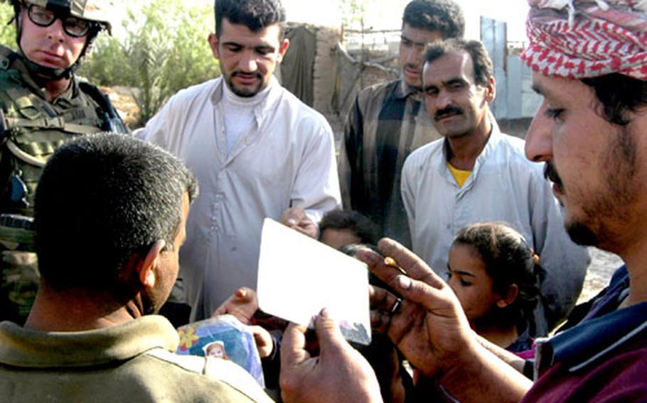 First Lt. Jimmy Ryan shows pictures of his family to an Iraqi family Wednesday in Ad-Daluiyah, Iraq. A few minutes later, he implored the adults in the group not to cooperate with the Iraqi insurgency.