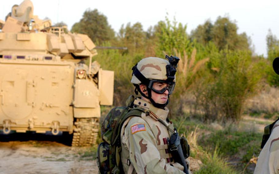 Spc. Michael Budahn, 20, of Chatfield, Minn., and Company A, 1st Battalion, 15th Infantry Regiment, goes on his first patrol Wednesday outside a base in Iraq. It also marked his first ride in a Bradley fighting vehicle, shown in the background.