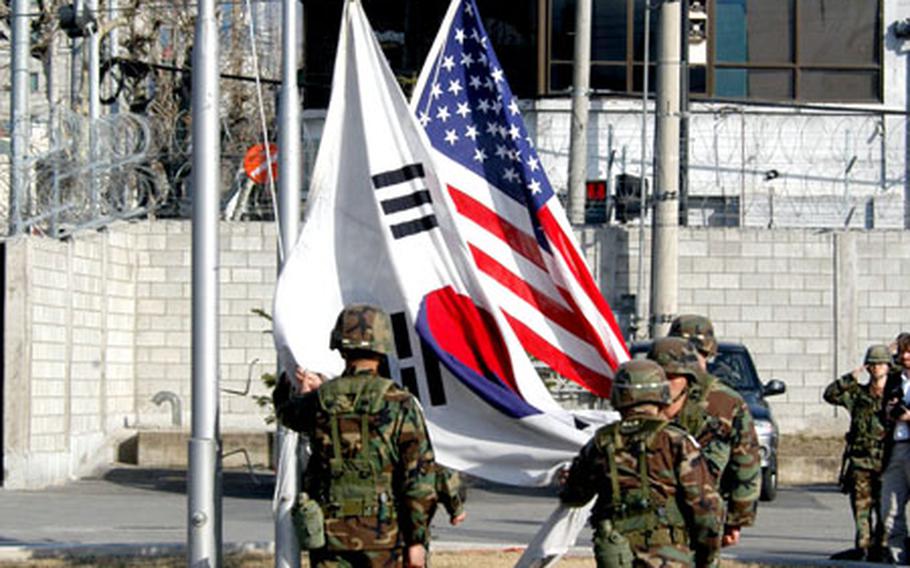 The U.S. and South Korean flags are lowered for the last time at Camp Page on Tuesday during a ceremony marking the closure of the U.S. base.