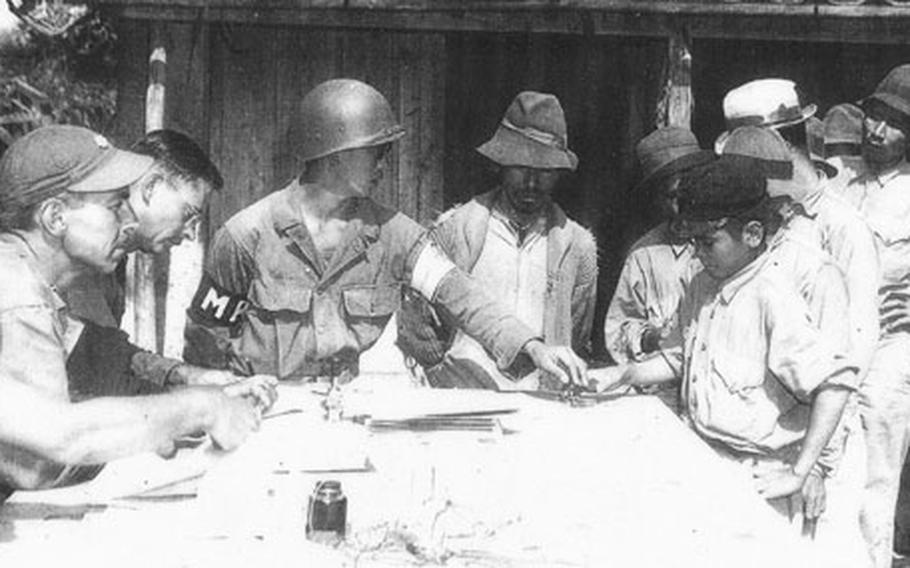 Teruto “Terry” Tsubota, center, wearing MP armband, registers Okinawa refugees during the Battle of Okinawa, which started 60 years ago.