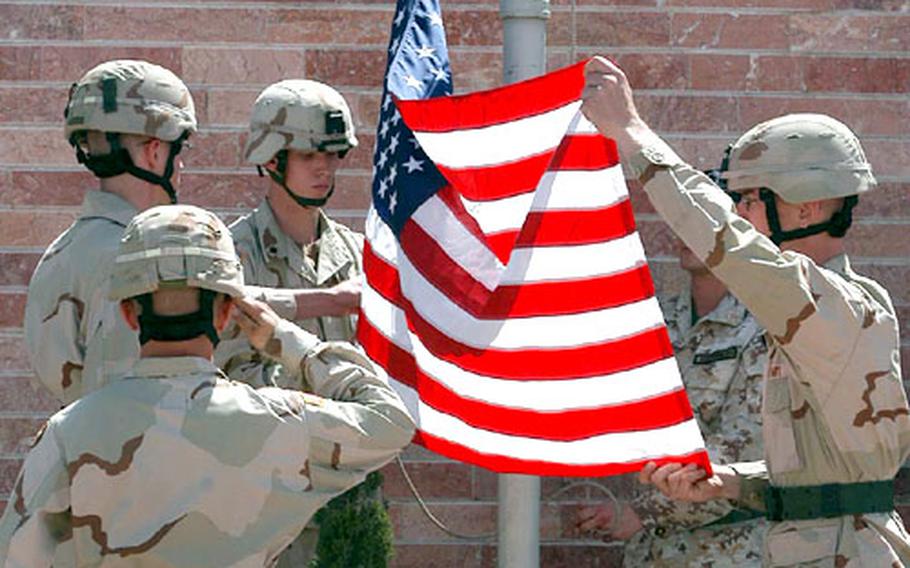 Sgt. Tom Estes salutes as Spc. Chris Jackson, Spc. Mike Elmer and Sgt. Eric Kilen, from left, take down the American flag during the Herat Provincial Reconstruction Team transfer of authority ceremony in Herat on Thursday.