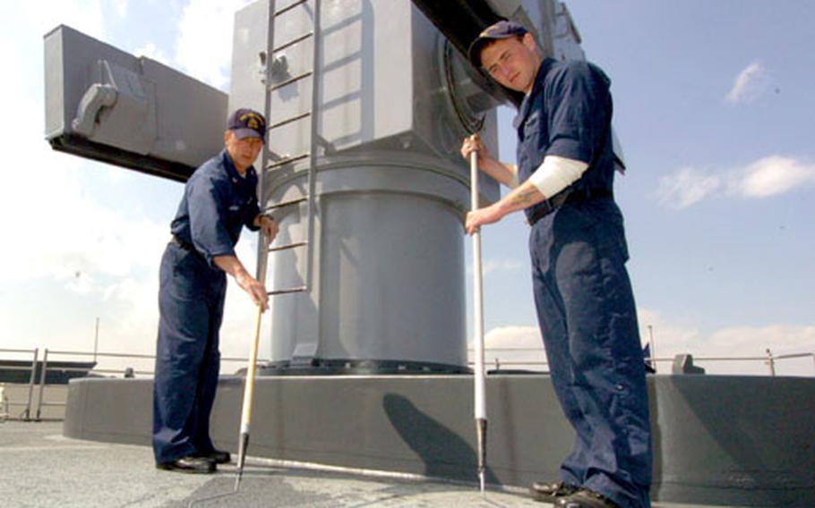Petty Officer 2nd Class William Arthur, left, from CO Division, and Petty Officer 3rd Class Charles Sager from CA Division, paint the missile deck on the USS Vincennes.