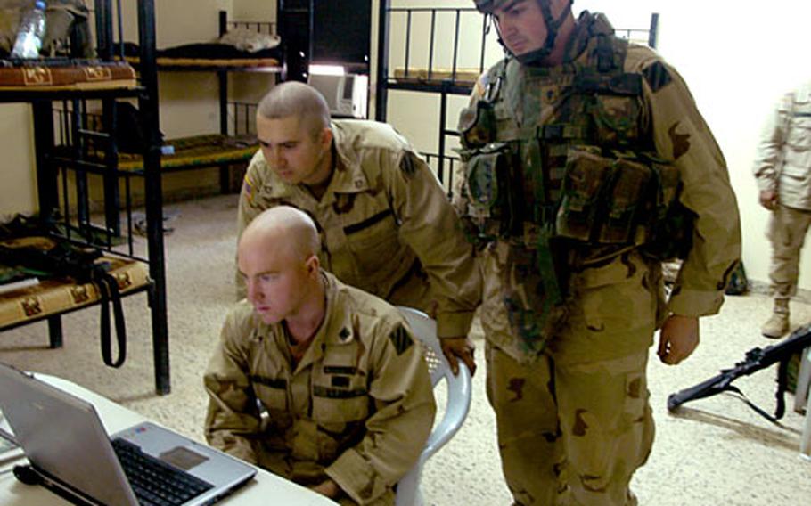 Soldiers from the 1st Battalion, 15th Infantry Regiment, read about the trial of Capt. Roger Maynulet trial via the Internet while at FOB MacKenzie, Iraq. The soldiers are Spc. John Kirkpatrick, sitting, Spc. Aaron Berghoff, right, and Pfc Christopher Cade.