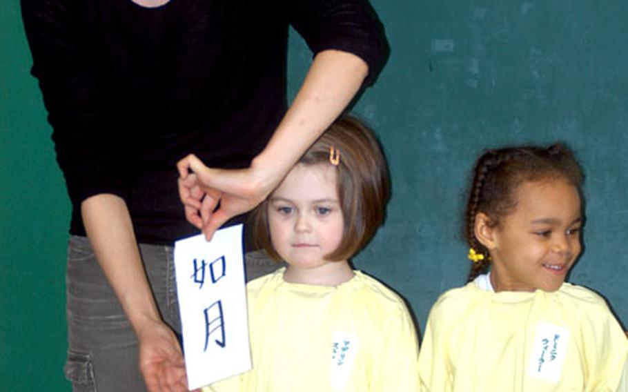 Madaline Stephens, left, and Dominique Wheeler, stand in line with Japanese character flash cards during a recent Parent&#39;s Day at Daiichi Yochien, a private kindergarten in Misawa city.