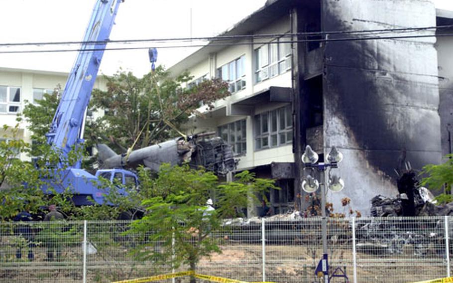 The tail section of the CH-53D Sea Stallion is removed from the crash site at Okinawa International University last August. The accident prompted a review of guidelines for handling off-base accidents involving U.S. military aircraft.