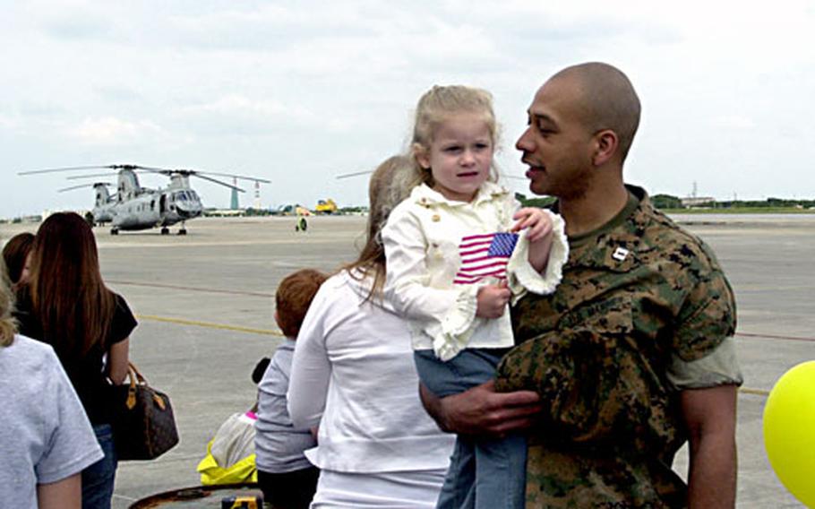 Capt. Amos Perkins waits with Tatum, 3, while her father, Capt. Benjamin DeBardeleben, and nearly 400 other Marines from the 31st Marine Expeditionary Unit debark from helicopters.