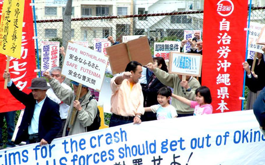 A father leads his daughters in a protest chant Friday during a demonstration by about 50 people outside Marine Corps Air Station Futenma, Okinawa. The group was protesting the return of U.S. Marines from Iraq.