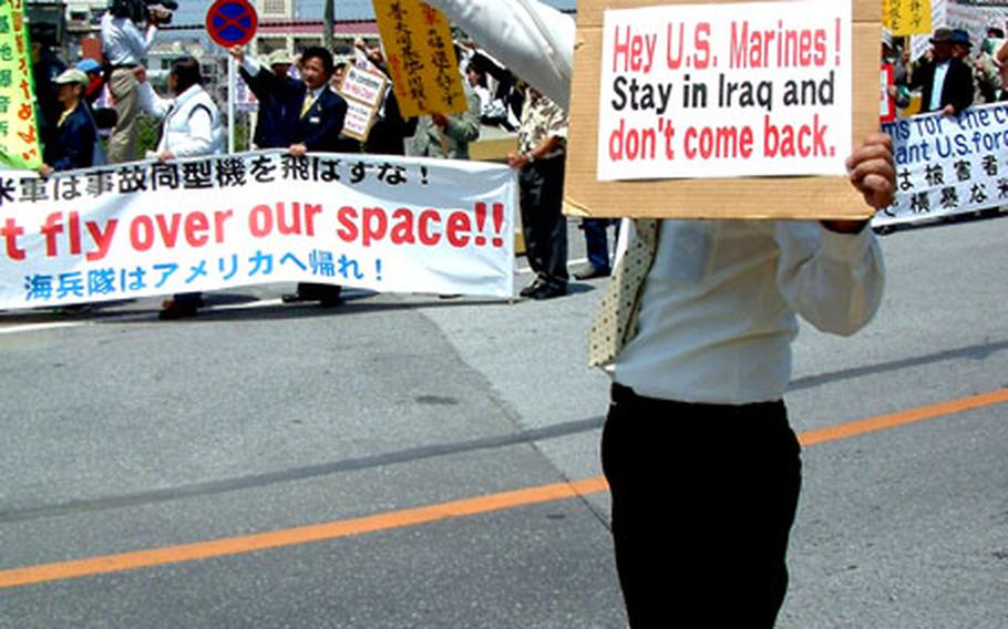 A protester holds a sign during Friday&#39;s demonstration outside Marine Corps Air Station Futenma on Okinawa.