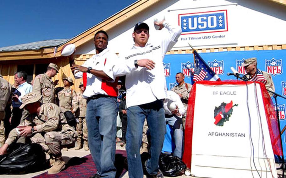 Atlanta Falcon Warrick Dunn, left, and New England Patriot Larry Izzo toss out autographed footballs to the troops before the ribbon-cutting ceremony to open the Pat Tillman USO Center on Bagram Air Base.