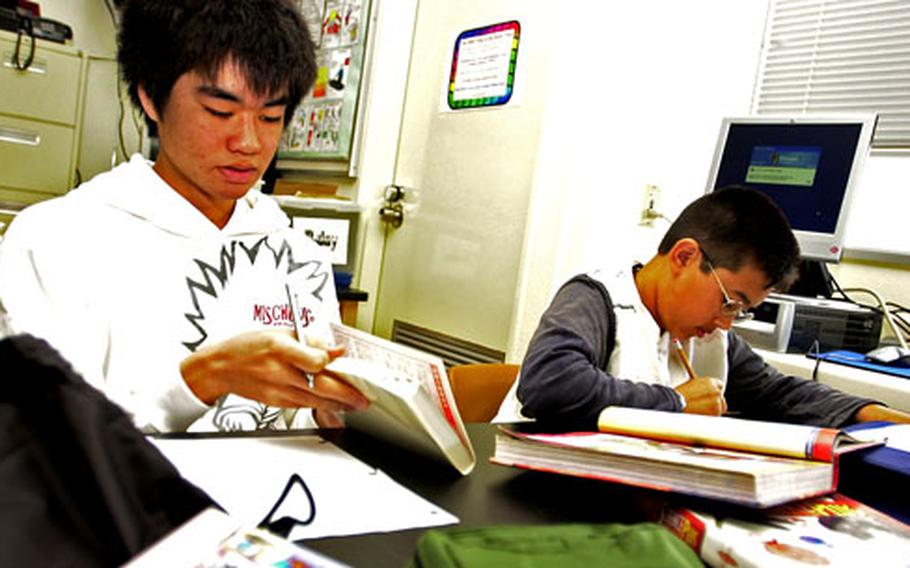 Genki Yoshimura, left, an eighth-grader from Yamauchi Junior High in Okinawa City, sits with his “sponsor” Billy Sherwood at Kadena Middle School during a science class Wednesday.